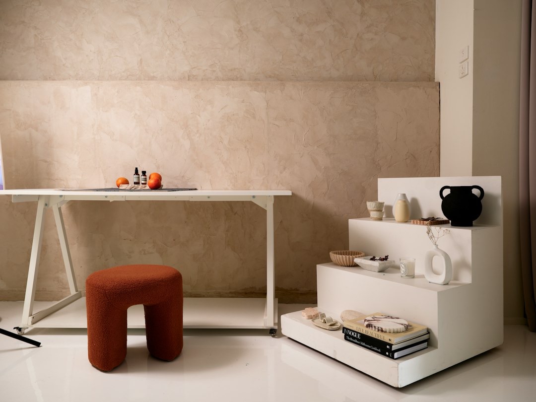 White table with Aesop bottles and oranges next to boucle stool.